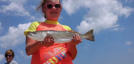 Smiling girl with fish caught aboard Rock On Charters.